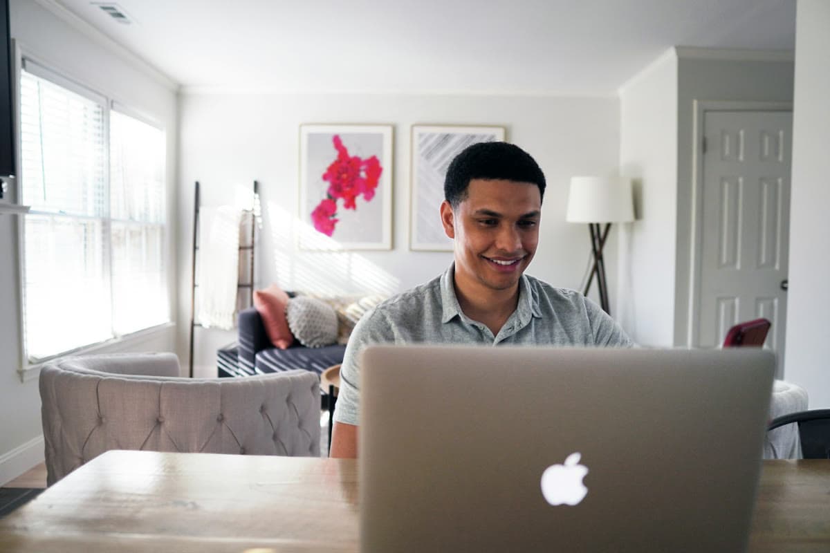 Pessoa sorrindo enquanto trabalha no notebook